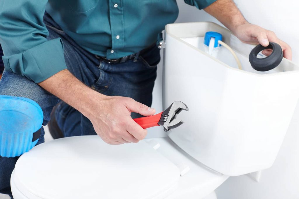 Plumber fixes a toilet.