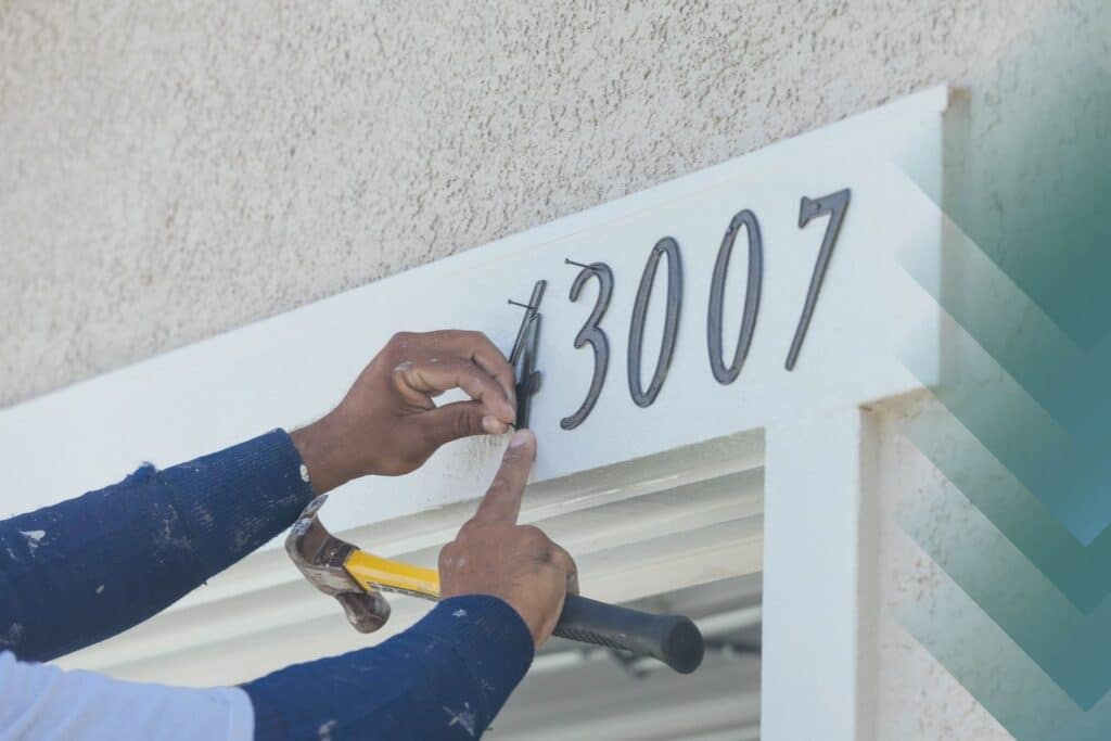 person hanging house address numerals
