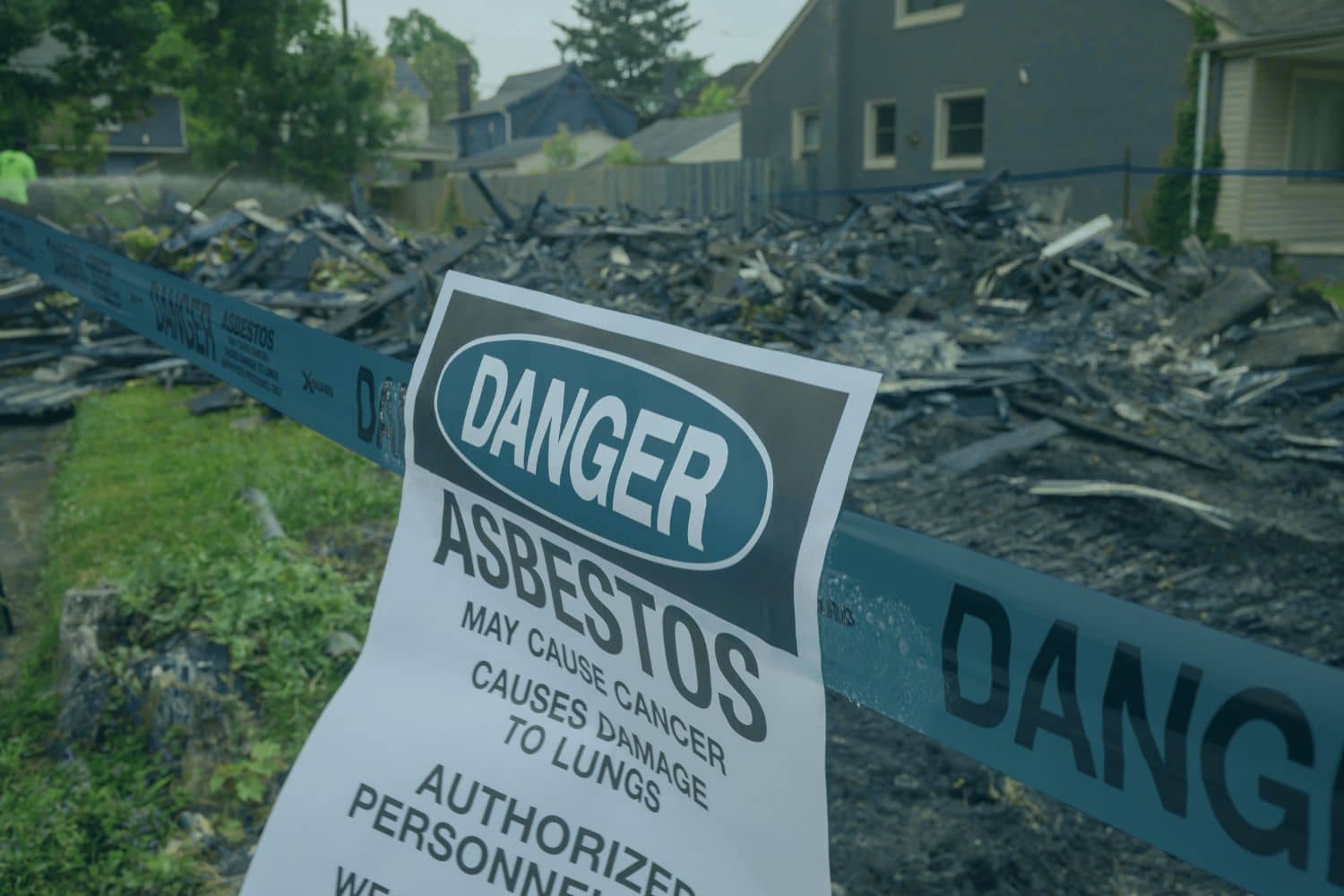 An asbestos danger sign posted at a residential home demolition site, warning about hazards like hidden asbestos walls.